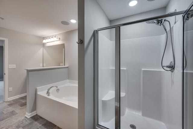 full bath with a shower stall, a bath, and baseboards