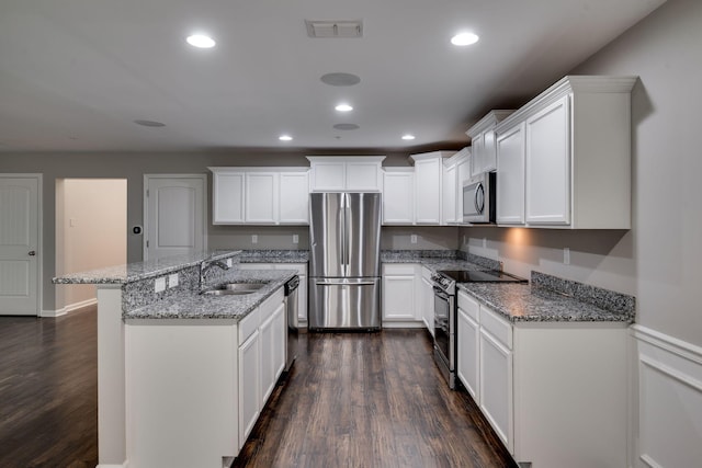 kitchen with stainless steel appliances, a sink, dark wood-style flooring, light stone counters, and white cabinetry