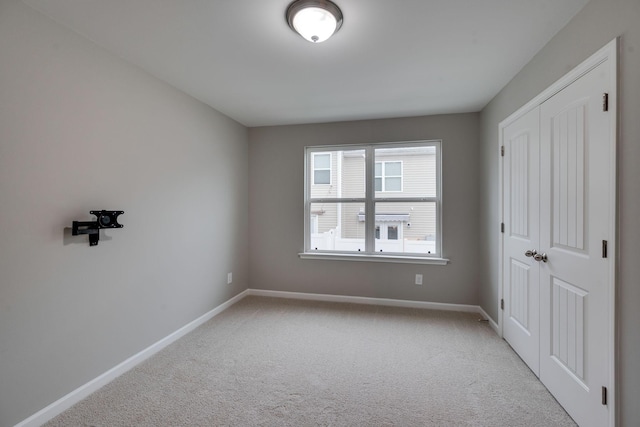 unfurnished bedroom featuring baseboards, carpet, and a closet