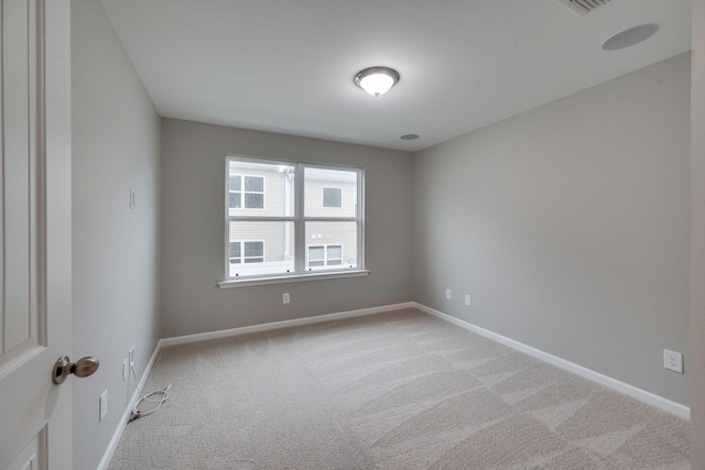 unfurnished room featuring light carpet and baseboards
