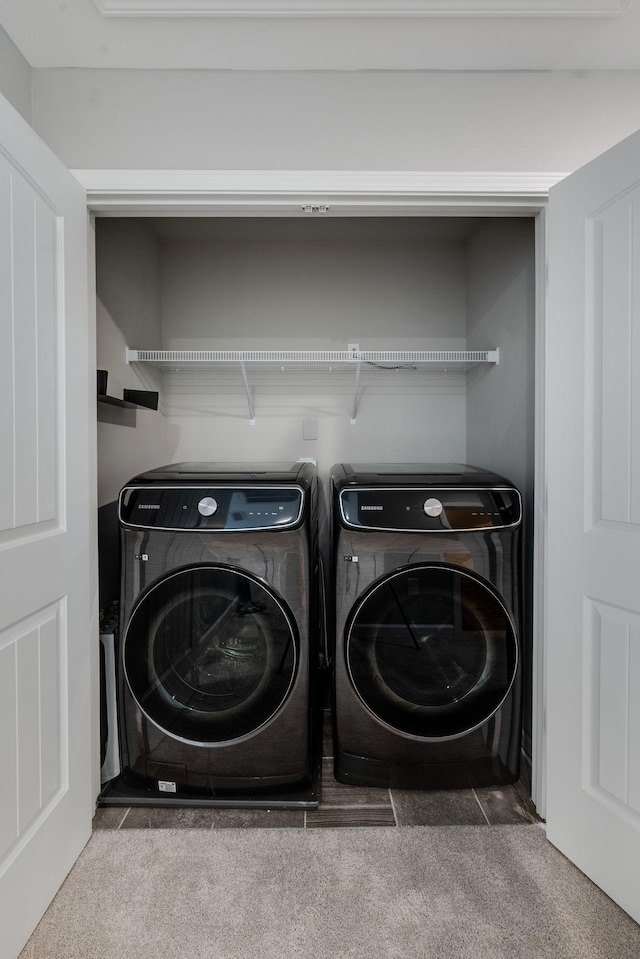 clothes washing area featuring washer and clothes dryer and carpet floors