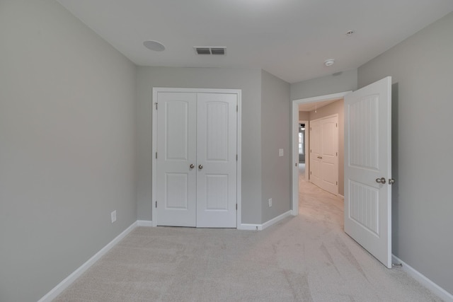 unfurnished bedroom featuring light carpet, baseboards, and a closet
