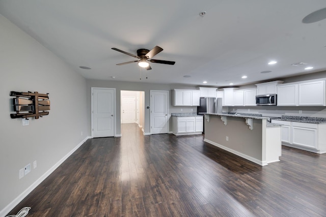 kitchen with appliances with stainless steel finishes, ceiling fan, baseboards, a kitchen breakfast bar, and light stone counters