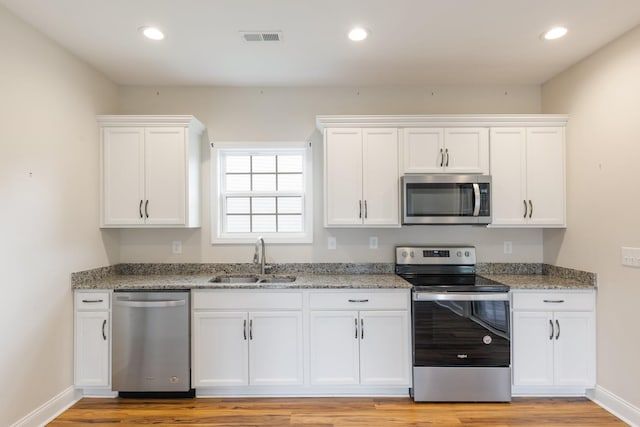 258 Jesse Dr, Pleasant View, TN 37146 - kitchen with stainless steel appliances, a sink, white cabinets, light wood-style flooring, and recessed lighting