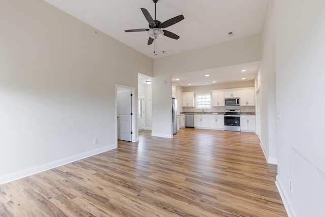 258 Jesse Dr, Pleasant View, TN 37146 - unfurnished living room with light wood finished floors, a sink, ceiling fan, baseboards, and a high ceiling