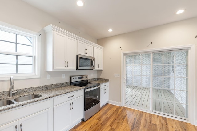 258 Jesse Dr, Pleasant View, TN 37146 - kitchen with appliances with stainless steel finishes, a sink, white cabinets, light wood finished floors, and light stone countertops