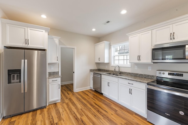 258 Jesse Dr, Pleasant View, TN 37146 - kitchen featuring appliances with stainless steel finishes, a sink, white cabinetry, light wood finished floors, and recessed lighting