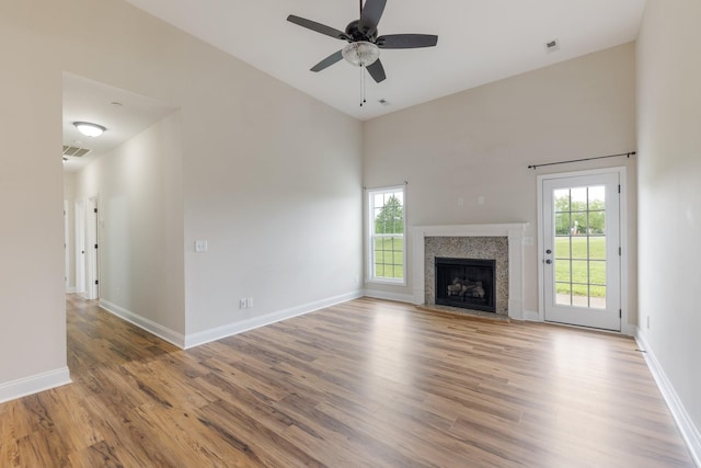 258 Jesse Dr, Pleasant View, TN 37146 - unfurnished living room featuring wood finished floors, a ceiling fan, baseboards, a fireplace with flush hearth, and a high ceiling