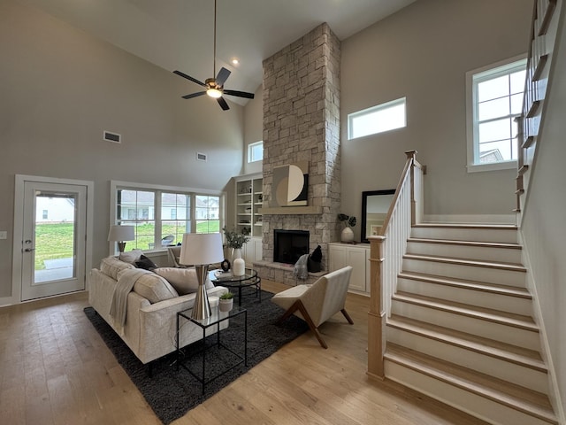 4109 Fargo Ct, Murfreesboro, TN 37127 - living room with a high ceiling, a ceiling fan, light wood-style floors, a stone fireplace, and stairway