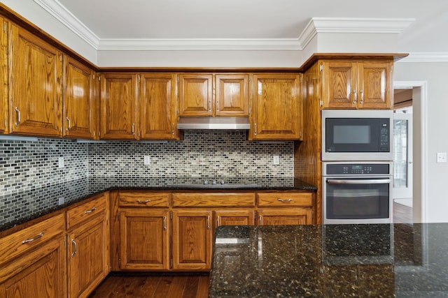 2506 Morgan Rd, Murfreesboro, TN 37129 - kitchen with black appliances, ornamental molding, brown cabinetry, under cabinet range hood, and dark stone countertops
