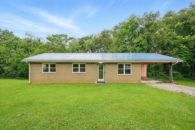 ranch-style house featuring metal roof, a front yard, gravel driveway, and an attached carport