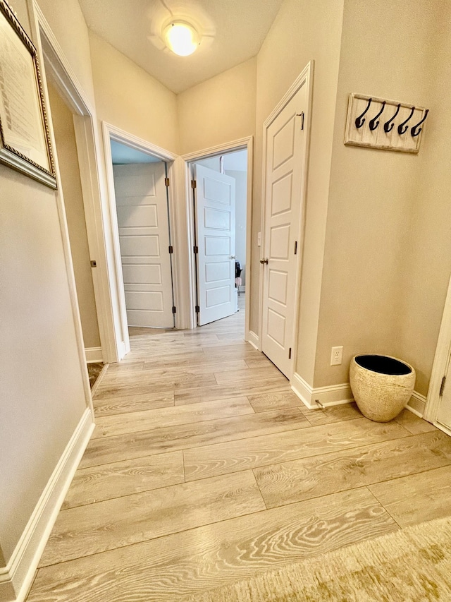 hall with light wood-style flooring and baseboards