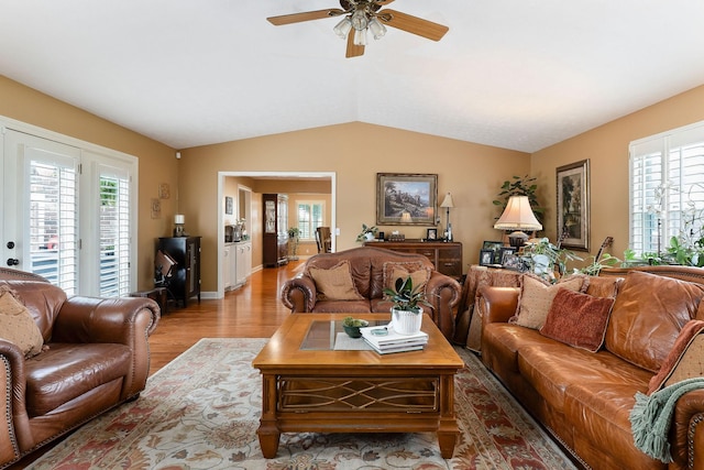 living room featuring a ceiling fan, wood finished floors, vaulted ceiling, healthy amount of natural light, and baseboards