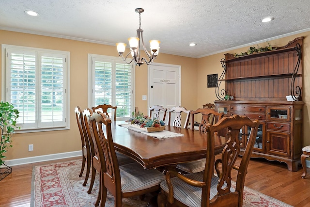 dining room featuring a chandelier, ornamental molding, wood finished floors, a textured ceiling, and baseboards
