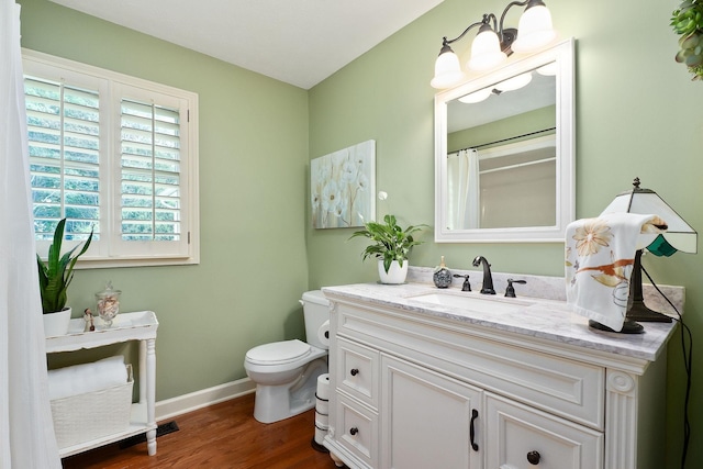 bathroom with wood finished floors, baseboards, toilet, and vanity