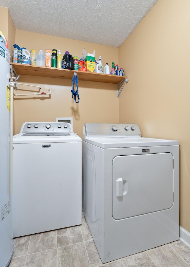 laundry room featuring washer and dryer, water heater, and a textured ceiling