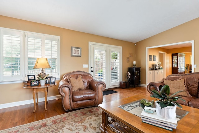 living area featuring wood finished floors, baseboards, and lofted ceiling