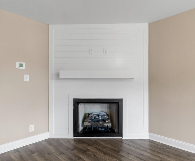 detailed view of a large fireplace, baseboards, and wood finished floors