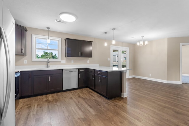 kitchen featuring stainless steel appliances, a sink, a peninsula, and wood finished floors