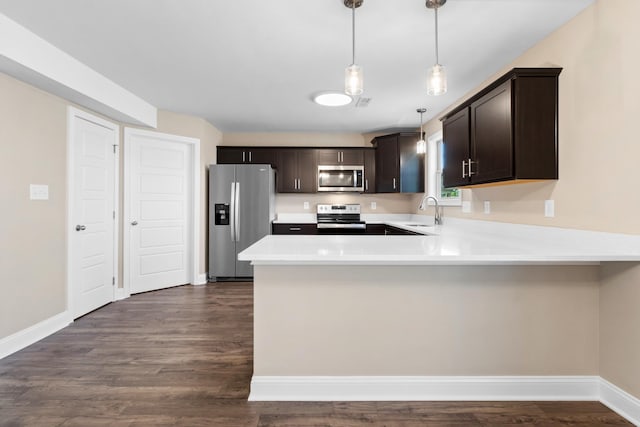 kitchen featuring appliances with stainless steel finishes, dark brown cabinetry, a peninsula, light countertops, and a sink