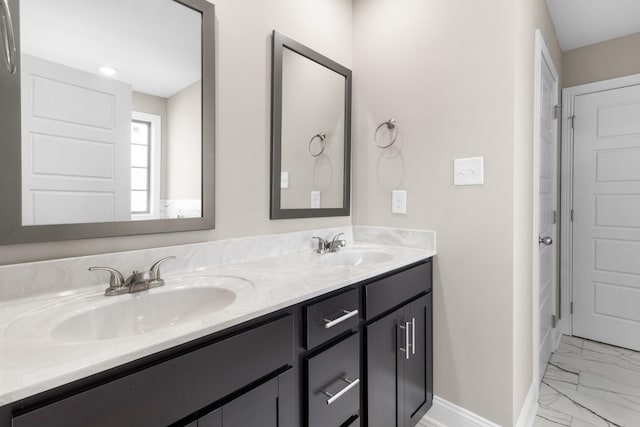 bathroom with marble look tile flooring, baseboards, and double vanity