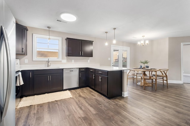 kitchen with stainless steel appliances, a sink, a peninsula, a chandelier, and wood finished floors