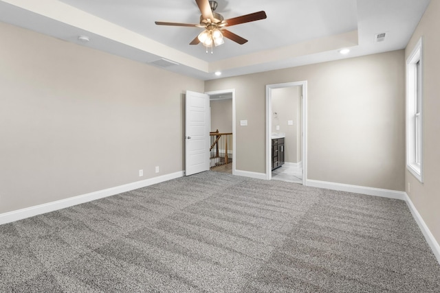 unfurnished bedroom with a tray ceiling, light carpet, baseboards, and ceiling fan