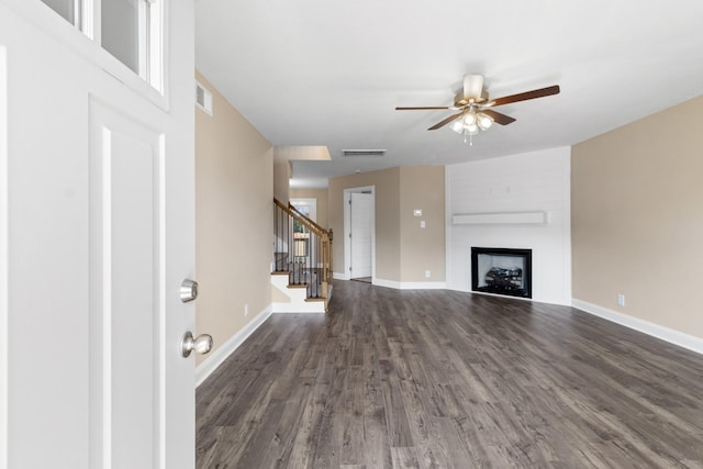 unfurnished living room featuring ceiling fan, dark wood-style floors, stairs, and baseboards