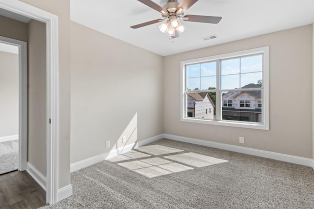 carpeted spare room with a ceiling fan and baseboards