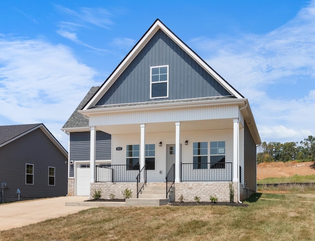 bungalow-style home with covered porch, concrete driveway, board and batten siding, a front yard, and a garage