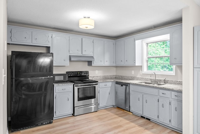 938 Merritt Lewis Ln, Clarksville, TN 37042 - kitchen featuring black appliances, a sink, under cabinet range hood, light wood-style flooring, and light stone countertops
