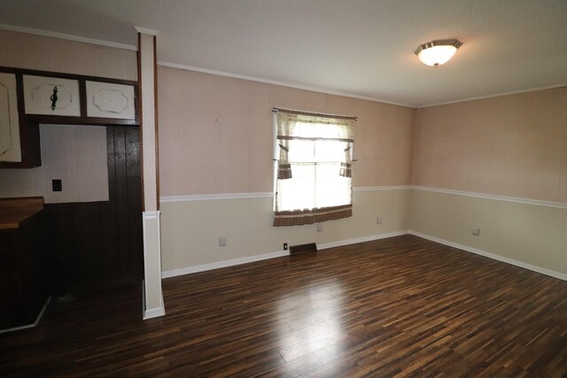 unfurnished room with dark wood-style floors, ornamental molding, and baseboards