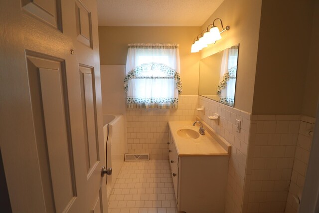 bathroom featuring tile patterned flooring, tile walls, vanity, and a wainscoted wall