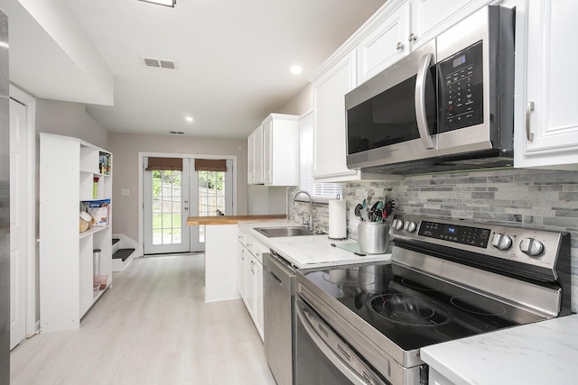 1543 James Gafford Dr, La Vergne, TN 37086 - kitchen featuring stainless steel appliances, a sink, white cabinets, backsplash, and light wood-style flooring