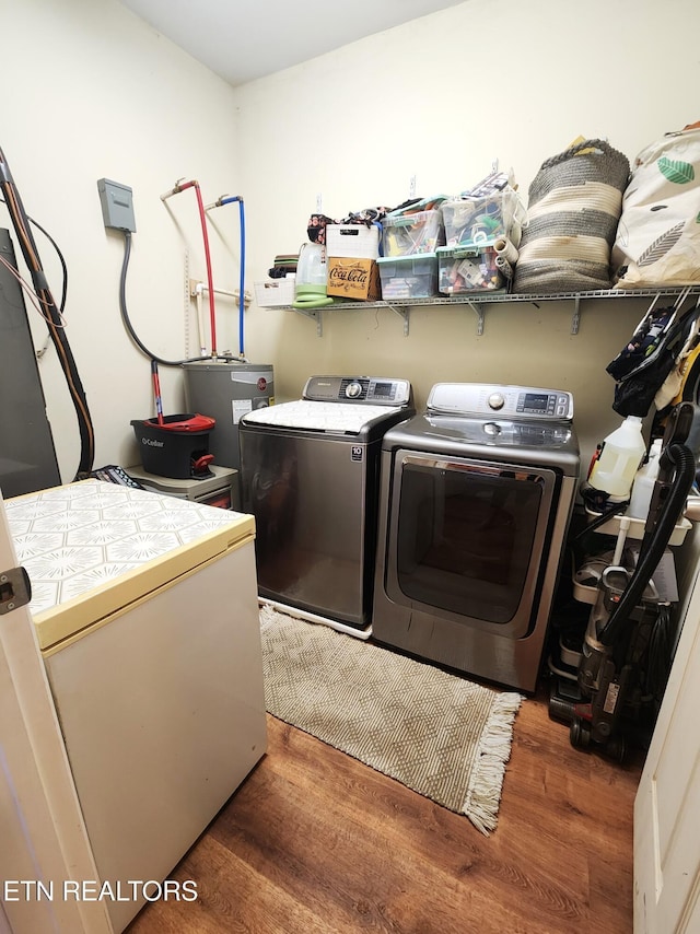 washroom featuring washing machine and clothes dryer, wood finished floors, and electric water heater