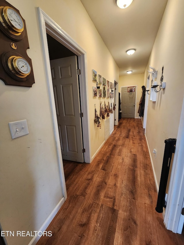 hallway with dark wood-type flooring and baseboards