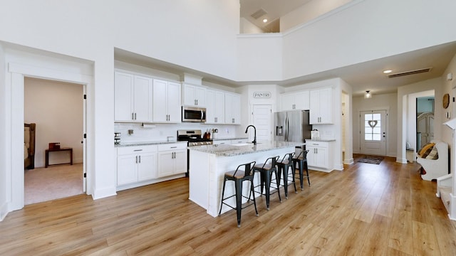 363 Turfway Park, Gallatin, TN 37066 - kitchen featuring appliances with stainless steel finishes, light wood-style flooring, a breakfast bar, white cabinets, and a towering ceiling