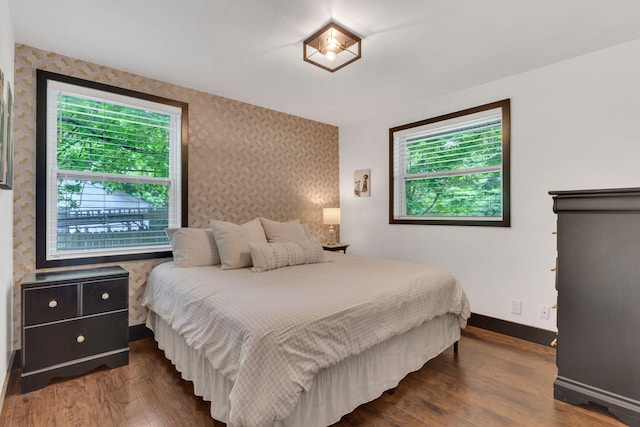 bedroom featuring wallpapered walls, baseboards, and dark wood-type flooring