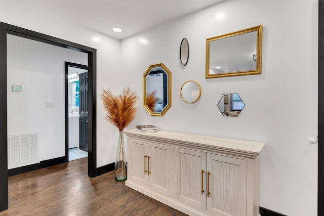 corridor featuring dark wood-type flooring and baseboards