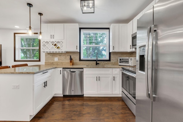 kitchen featuring appliances with stainless steel finishes, a sink, a peninsula, white cabinets, and recessed lighting