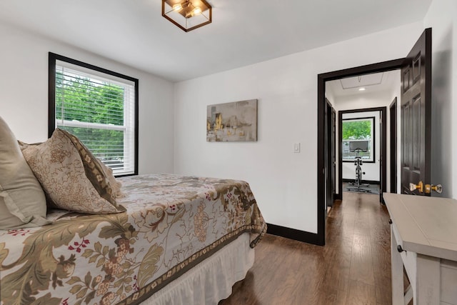 bedroom featuring multiple windows, wood finished floors, baseboards, and attic access