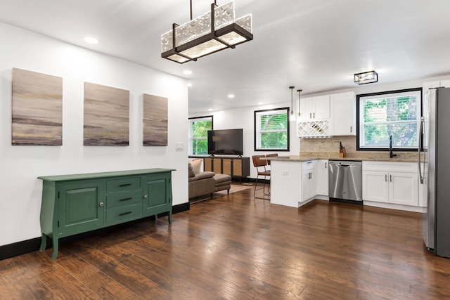 kitchen featuring appliances with stainless steel finishes, white cabinets, open floor plan, dark wood-style flooring, and decorative backsplash