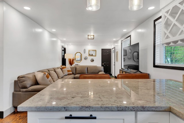 kitchen with wood finished floors, white cabinets, open floor plan, light stone countertops, and recessed lighting
