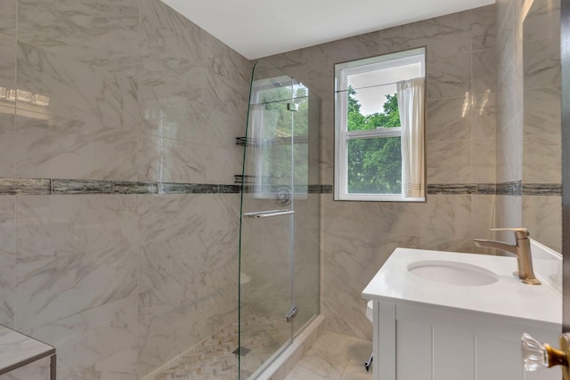 full bathroom with a shower stall, vanity, tile walls, and marble finish floors