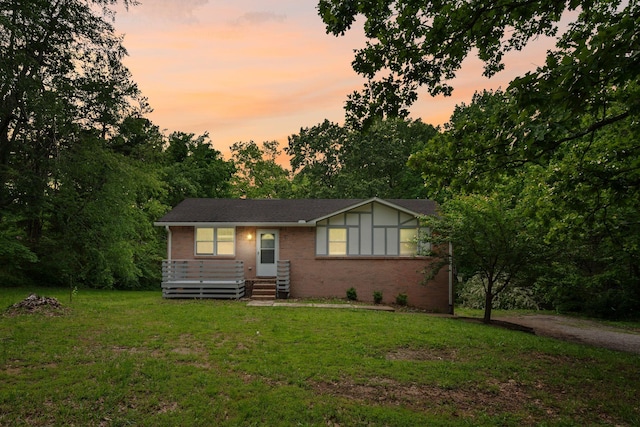 view of front of home with brick siding and a yard
