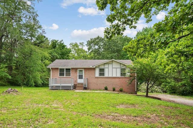 view of front facade with brick siding, a front yard, and a shingled roof