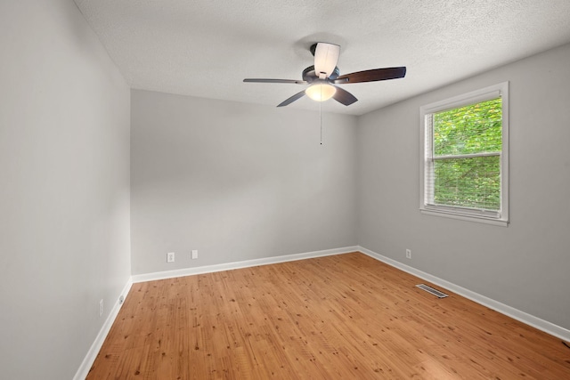 spare room featuring light wood-type flooring, baseboards, a ceiling fan, and a textured ceiling