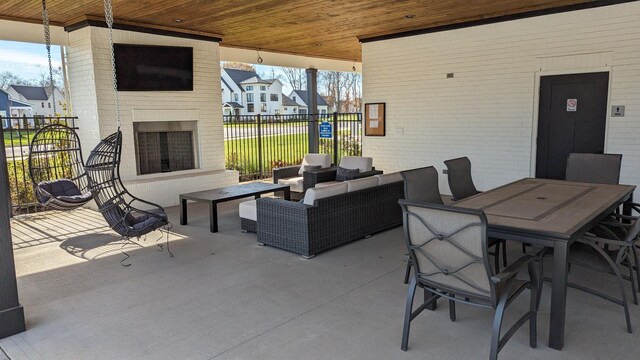 view of patio / terrace featuring fence, an outdoor living space with a fireplace, outdoor dining area, and a residential view