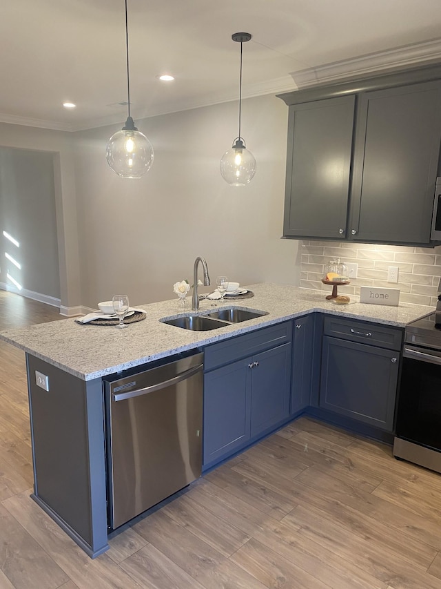 kitchen featuring appliances with stainless steel finishes, a sink, crown molding, a peninsula, and tasteful backsplash
