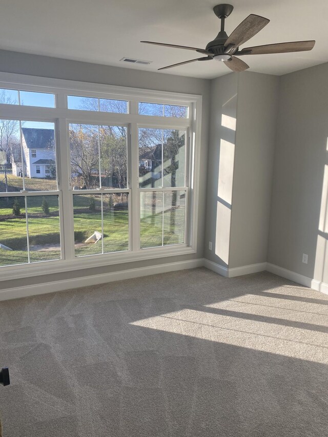 empty room with carpet flooring, a ceiling fan, and baseboards